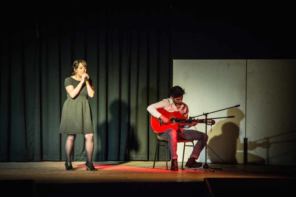 Une jeune fille chante accompagnée d'un guitariste